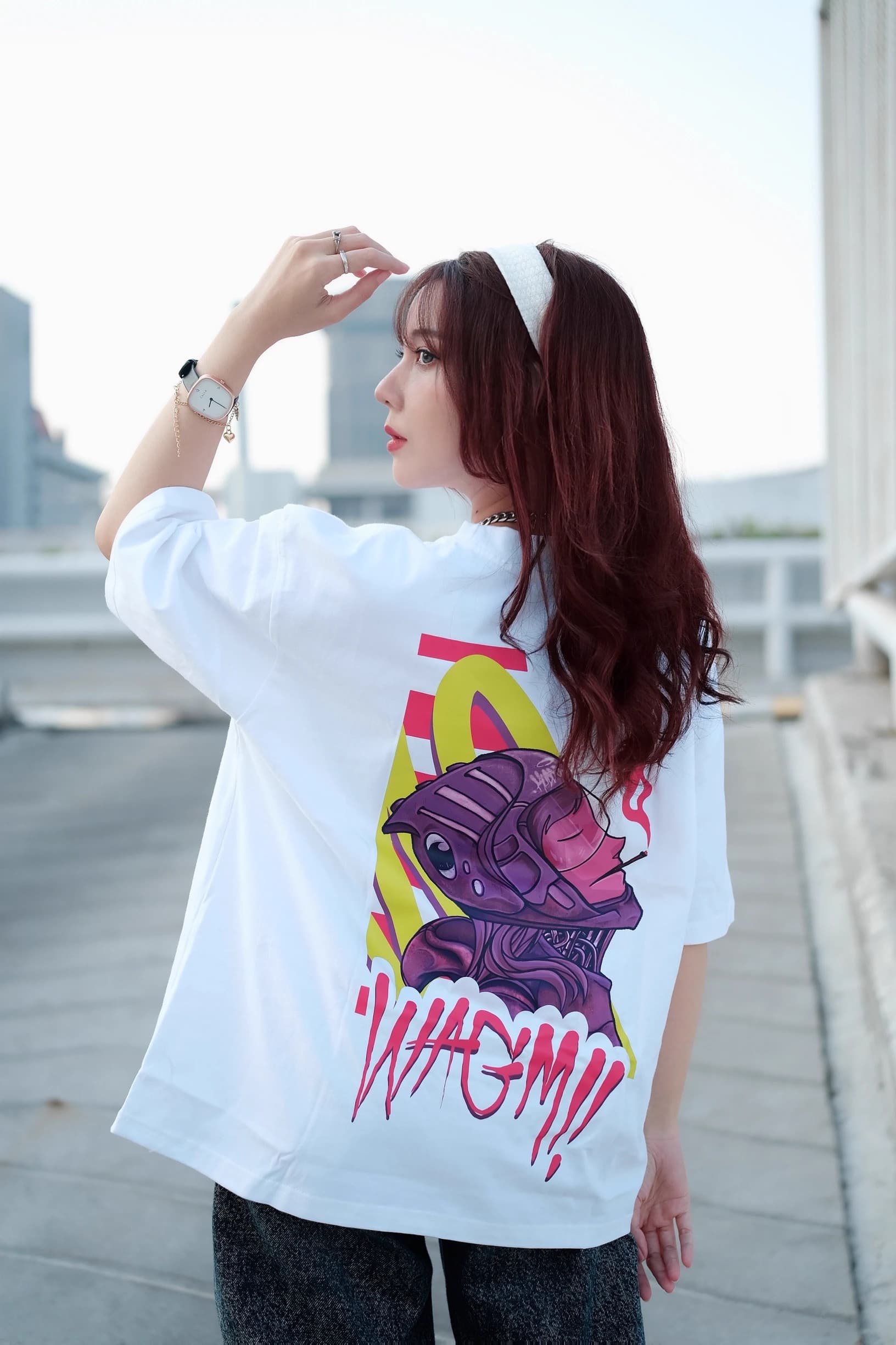 Woman looking sideways on a rooftop in a white T-shirt with a colorful back graphic